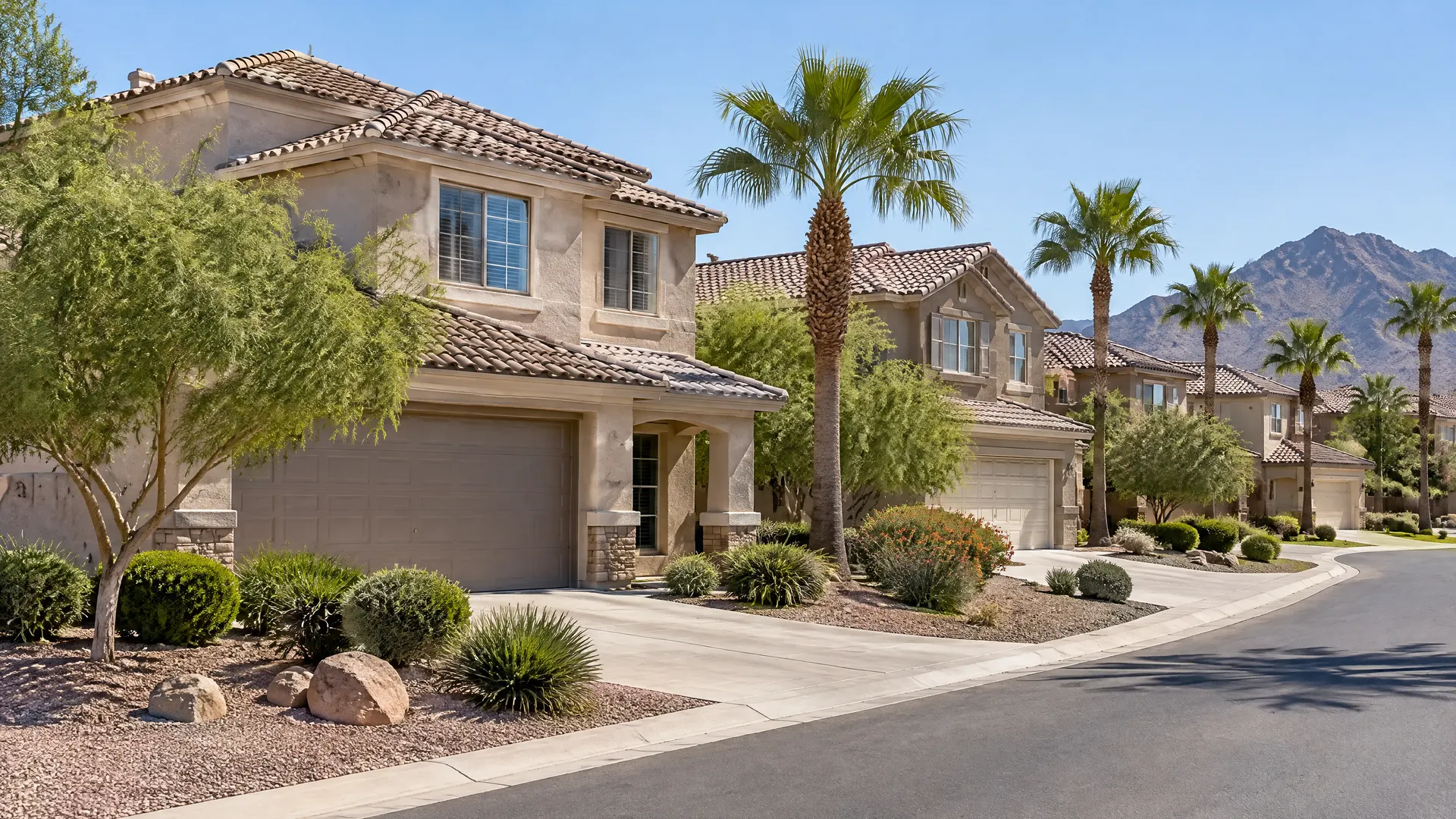 Two-story family homes with S-tile concrete roofs along a curving street, palm trees and desert landscaping in a Chandler subdivision